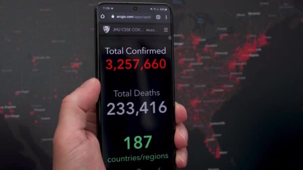 在Coronavirus分发美国地图前面的智能手机显示屏上的Coronavirus分发信息 — 图库视频影像