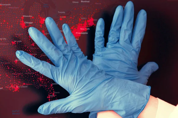 Hands in medical gloves in front of coronavirus spread USA map