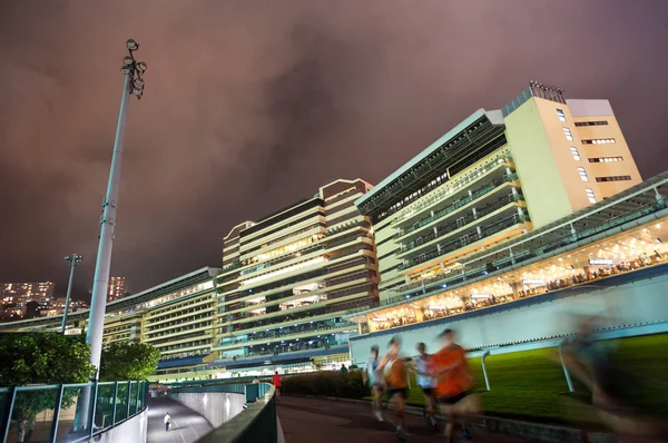 Lokale Hong Kong lopers lopen rond het spoor bij Happy Valley Stockfoto