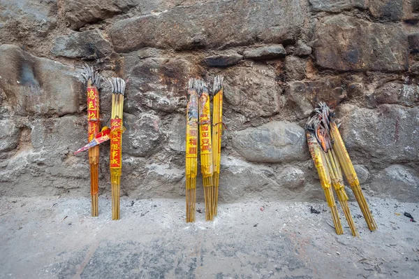 Paquetes de varillas de incienso apoyadas en una pared de piedra en un templo chino —  Fotos de Stock