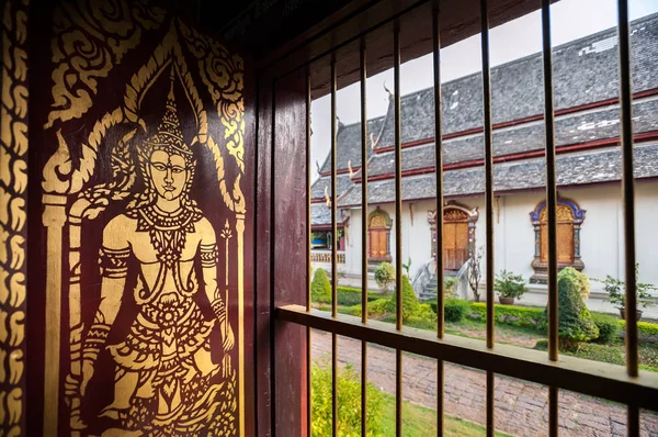 Gold-painted Buddha image on a wooden shutter inside the main Wiharn of Wat Chiang Man, Chiang Mai, Thailand — Stock Photo, Image