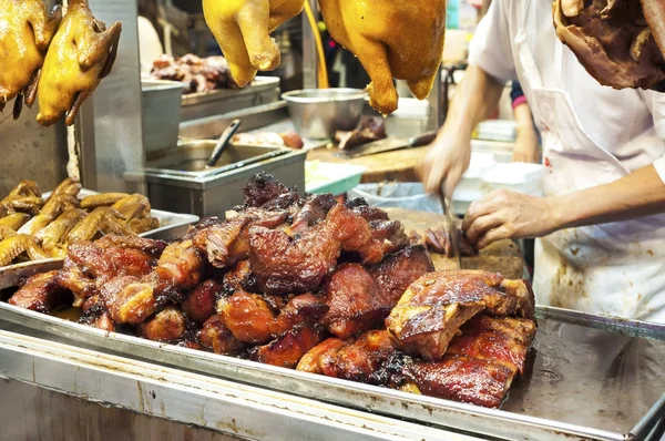 Butcher cutting barbequed pork, also known as cha siu, at a Hong Kong meat stall — Stock Photo, Image