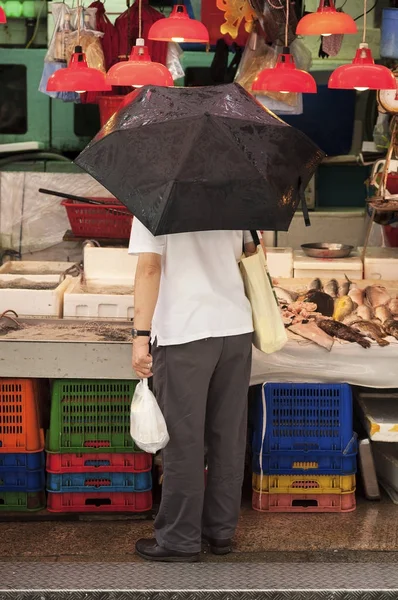 Hombre sosteniendo un paraguas en un puesto en el mercado húmedo de Graham Street , —  Fotos de Stock