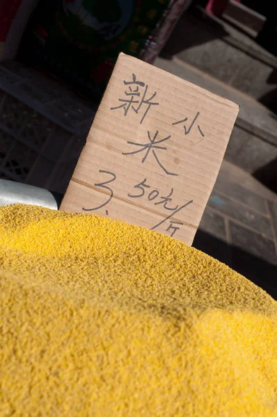 Yellow millet on sale at a Chinese market. The text reads 'new millet, 3.50 yuan/500g' — Stock fotografie