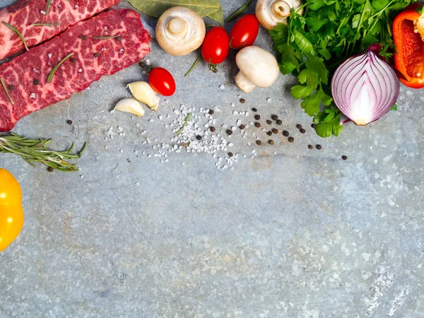 Çiğ et teneke bir sayfada. Yakındaki baharatlar, çeşniler ve sebze. Görünümün üst.