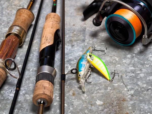 Spinnings, reel and baits on a sheet of tin.