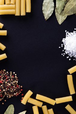 Makarna ve siyah bir zemin üzerine baharat.