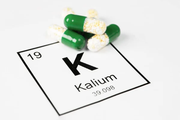 Yeşil haplarla maden K (Kalium) ile beyaz bir arka plan üzerinde bir