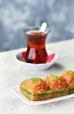 BAKLAVA. Geleneksel Türk Tatlıları Baklava ve Türk Çayı. Beyaz tabakta çıtır fıstıklı baklava..