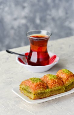 BAKLAVA. Geleneksel Türk Tatlıları Baklava ve Türk Çayı. Beyaz tabakta çıtır fıstıklı baklava..