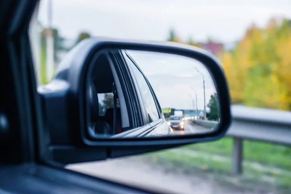 O reflexo da estrada com carros no retrovisor espelho de tráfego de automóveis à noite — Fotografia de Stock