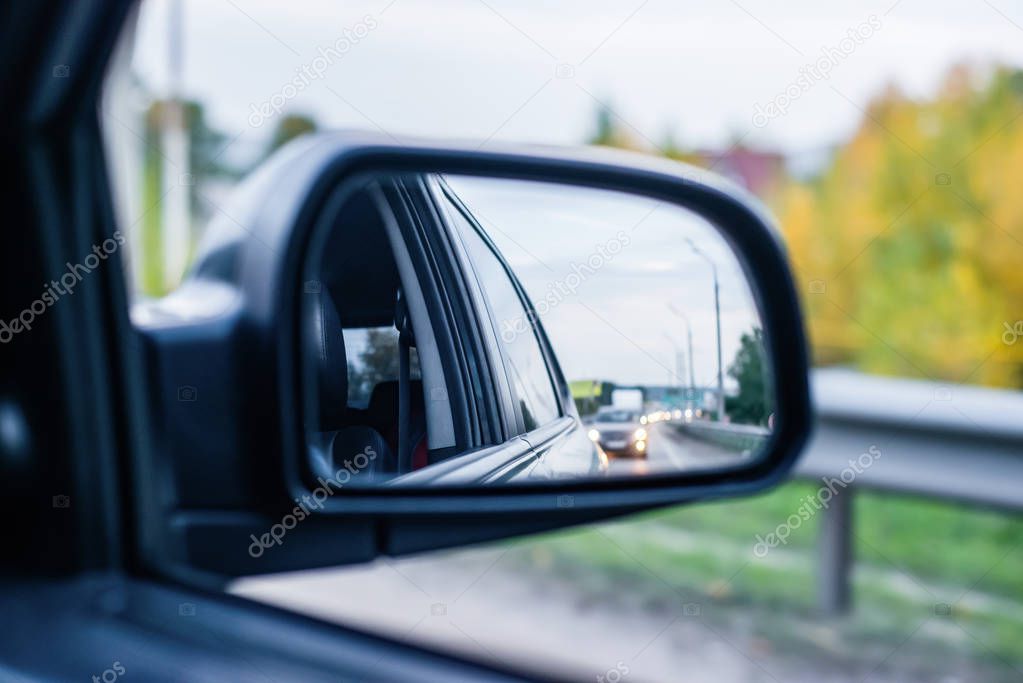 the reflection of the road with cars in the rearview mirror car traffic in the evening