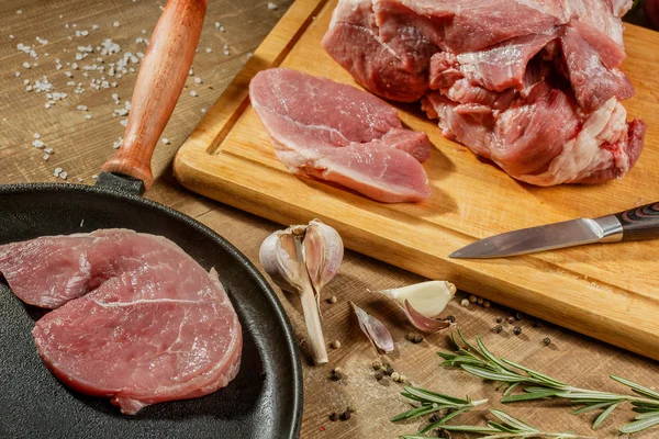 Raw pork steak in a frying pan on a kitchen table — Stock Photo, Image