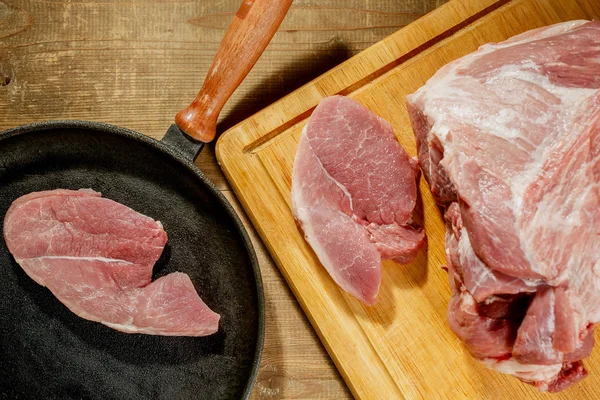 Raw pork steak in a frying pan on a kitchen table — Stock Photo, Image