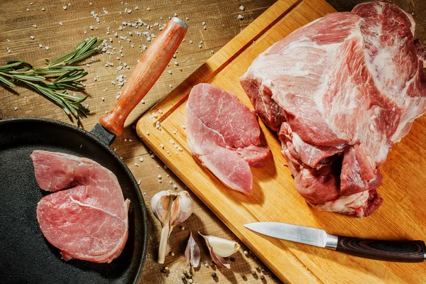 Raw pork steak in a frying pan on a kitchen table — Stock Photo, Image