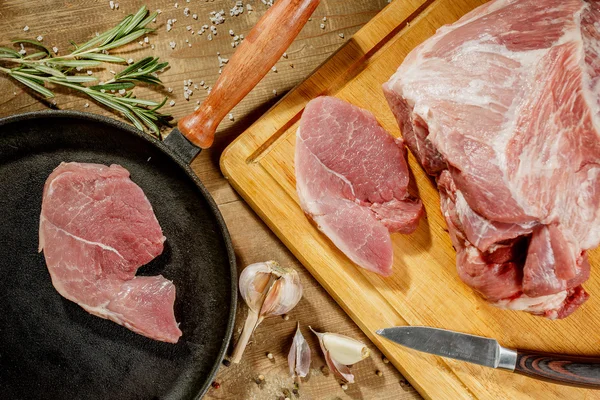 Raw pork steak in a frying pan on a kitchen table — Stock Photo, Image