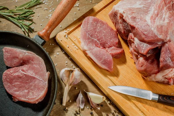 Raw pork steak in a frying pan on a kitchen table — Stock Photo, Image