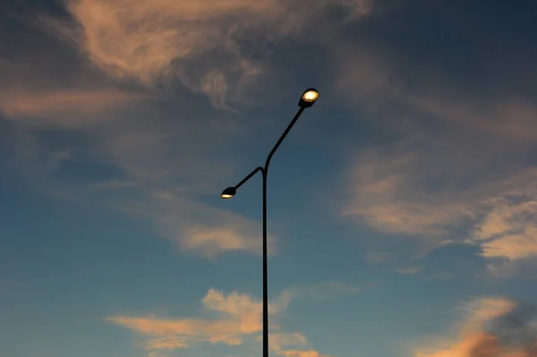 Bulutlu Bir Gökyüzüne Karşı Iki Işıkla Sokak Lambası Yakmak Batan Telifsiz Stok Fotoğraflar