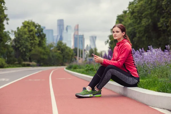 Joven mujer fitness escuchando música y descansando después de trotar —  Fotos de Stock