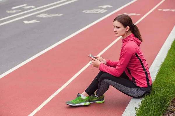 Joven mujer fitness escuchando música y descansando después de trotar —  Fotos de Stock