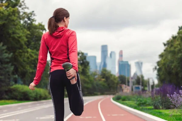 Joven atleta mujer corredor estira sus piernas antes de correr al aire libre Fotos de stock libres de derechos