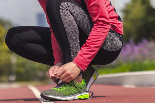 Runner pige binde hendes snørebånd mens jogging - Stock-foto