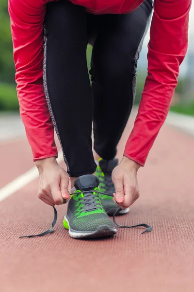 Runner pige binde hendes snørebånd mens jogging - Stock-foto