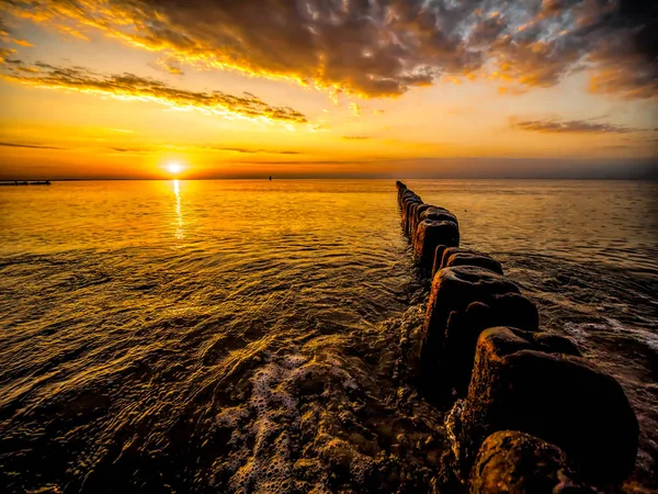 Old wooden wave breakers against the sunset