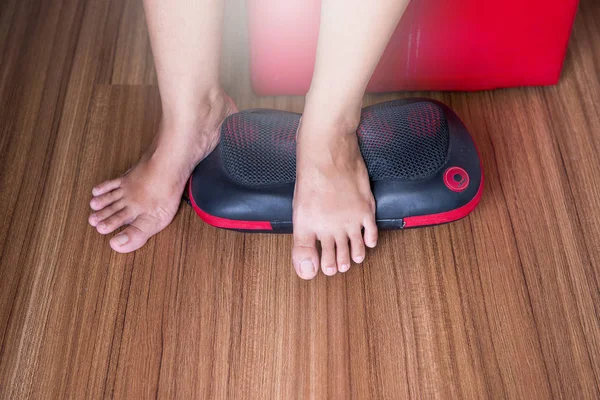 Woman using electric massage machine with foot