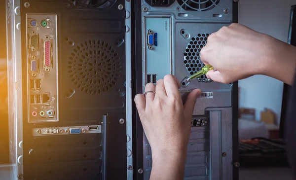 Hand with screwdriver fixing or repairing computer