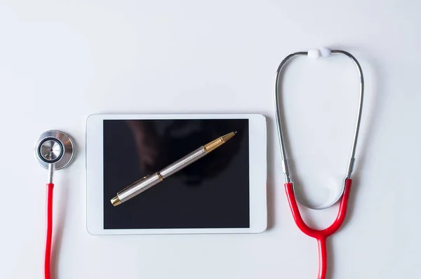 Stethoscope red color on tablet and pen on white background,Healthcare and medical concept