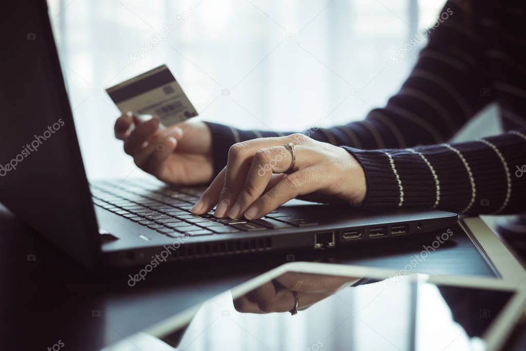 Close up of hand woman holding credit card and using laptop for online shopping concept