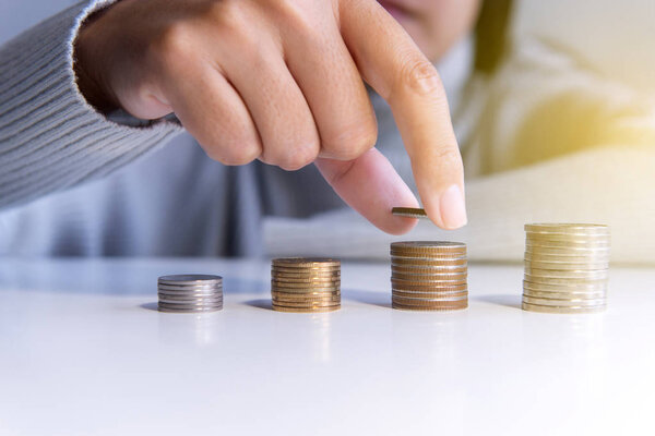 Hand putting money coins to stack and growing on a table,Saving money concept,Selective focus