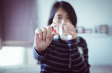 Hapları veya kapsül el ve bir bardak su, sağlık, seçici odak için kavramı ile genç Asyalı kadın
