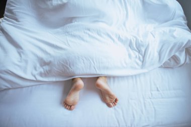 Yalınayak ve bacak battaniye yatak altında