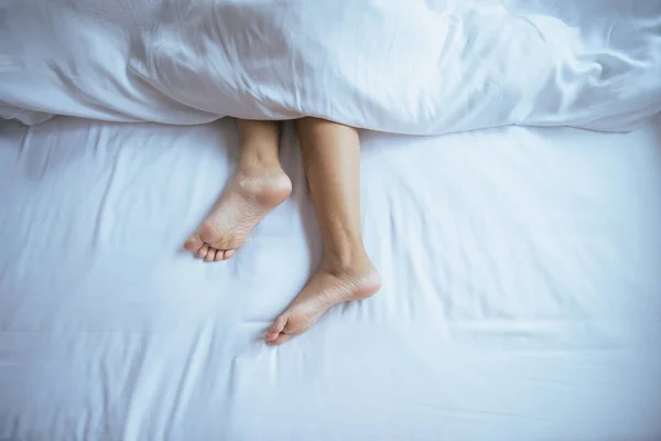 Barefoot and leg under blanket on the bed,Top view