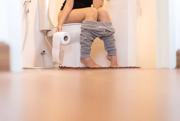 Woman using toilet after wake up in morning,Pants is hanging on her legs