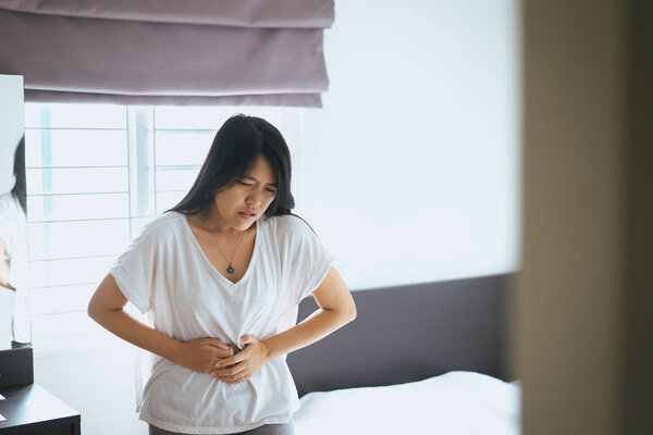 Asian female having painful stomachache,Woman suffering from abdominal pain,Period cramps