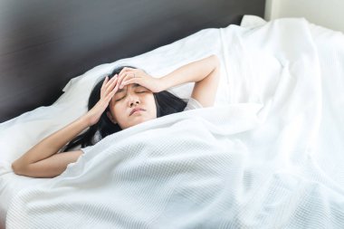 Asyalı kadın yatakta bir baş ağrısı uyku modundan çıkarma sonra sabah olacak