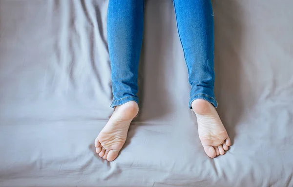 Close Pernas Mulher Com Jeans Azul Pés Esticar Preguiçosamente Cama — Fotografia de Stock