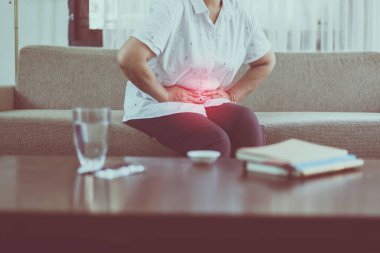 Evde ağrılı olan yaşlı asyalı kadın, Karın ağrısı çeken kıdemli kadın