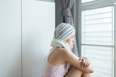 Kanserli Asyalı genç kadınlar bir şeye bakıyor ve evde oturuyor. Kadın depresyona giriyor ve üzülüyor.