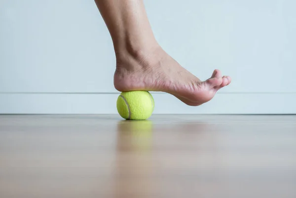 Yatak odasında ayağına tenis topu ile kadın masajı, ayak tabanı ya da plantar fasiit için topuklu masaj.