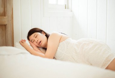 Asian woman snoring because due to tired of work,Female snor while sleeping on bed clipart