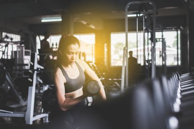 Sportif Asyalı güzel bir kadın halterli bir kadın spor giyim mağazasında spor yapıyor.