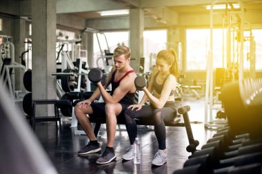 Sportif erkek ve kadın egzersizleri, halterleri kaldırma egzersizleri spor kıyafetleri giyen birkaç kişi spor salonunda egzersiz yapıyor.