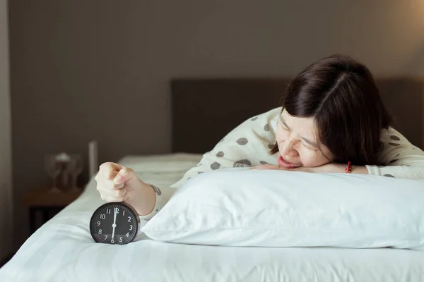 アジアの女性は早起きストレスを取得嫌い6時頃 目覚まし時計 週末の朝 — ストック写真