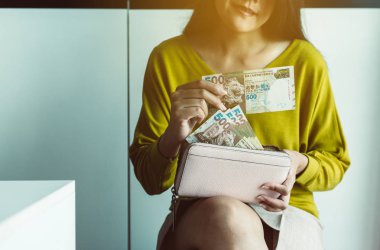 Beş yüz Hong Kong banknotunu sayan eller.