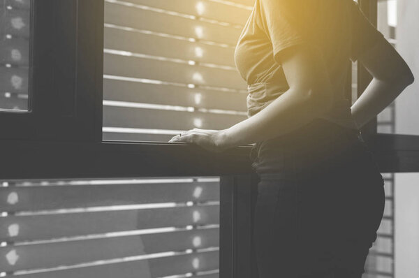 Woman disappointed in life while standing near window at home,Suicide prevention,Positive attitude and open mind,Mental health care concept,Black and white toned