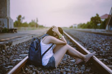 Depresyondaki Asyalı kadın tren istasyonunda oturuyor, olumsuz tutum, intihar önleme konsepti.